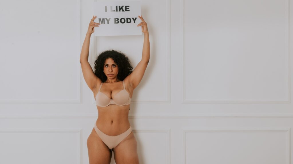 Camming benefits for mental health: Woman holding 'I Like My Body' sign