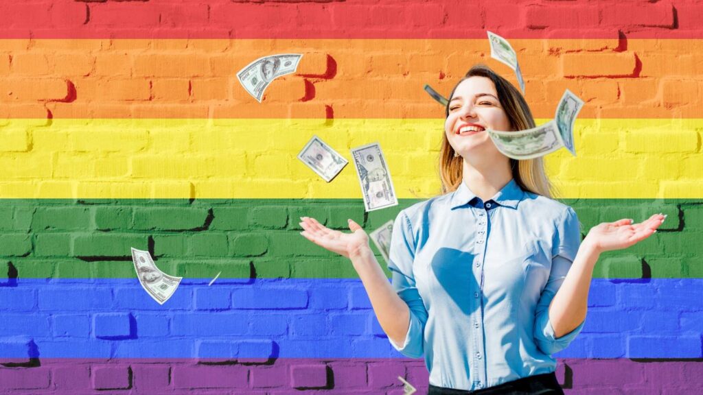 Woman throwing money in the air in front of a rainbow painted LGBTQIA+ Pride brick wall