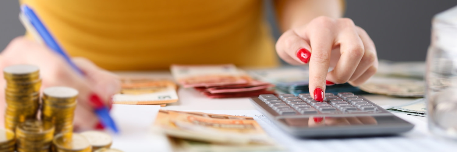 Woman using a calculator to count Chaturbate tokens and money, illustrating the process of calculating the value of tokens in dollars